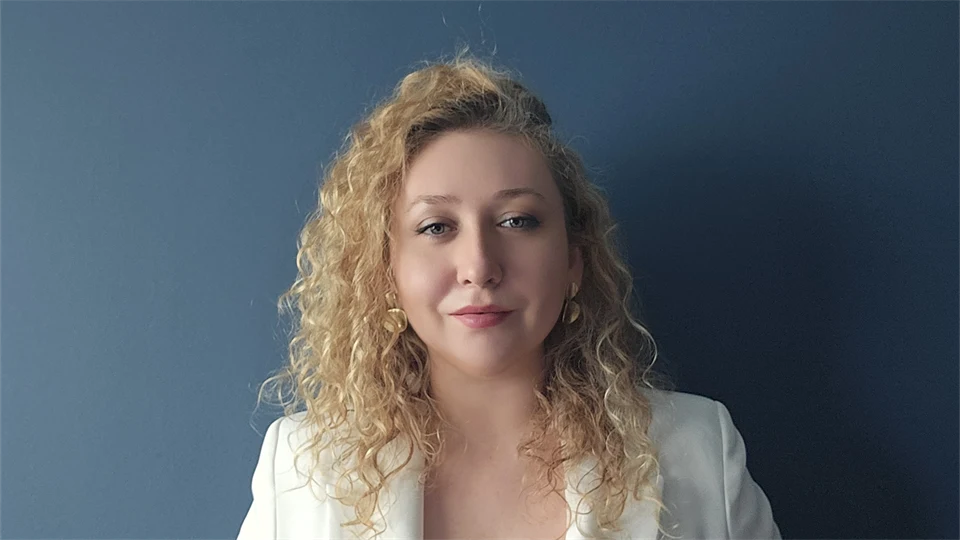 Young woman dressed in white in front of dark background