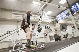 Alfred Buskqvist åker rullskidor på rullband med testutrustning som mäter syreupptagning, övervakas av testledare Hampus Lindblom.