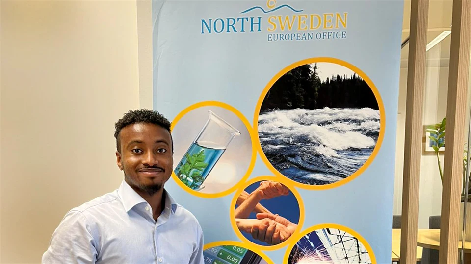 Man står framför en rollup som visar bilder av norra Sverige.