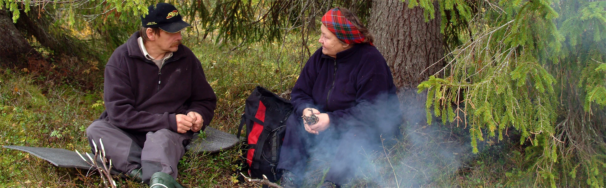En man och en kvinna samtalar vid en kaffeeld under en gran.