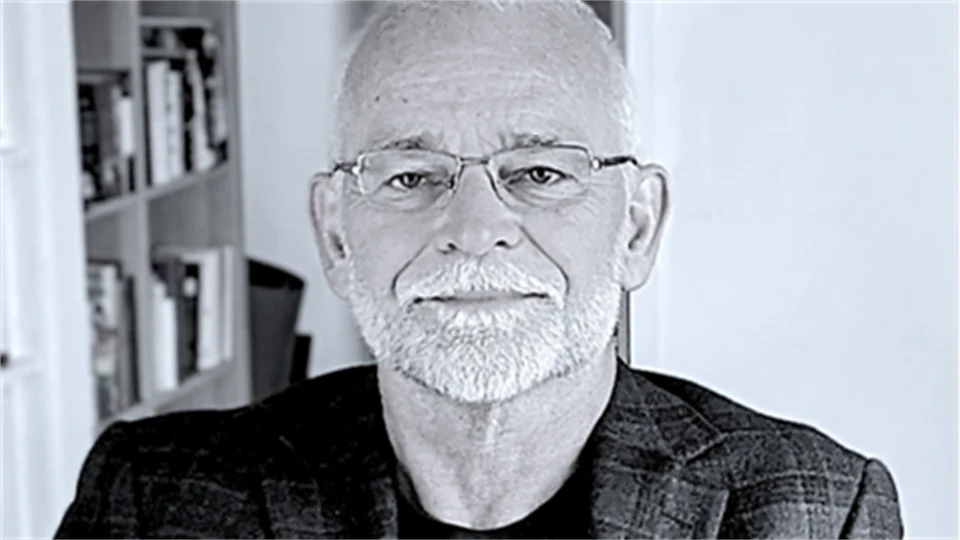 En grå bild på en man i kavaj framför en bokhylla