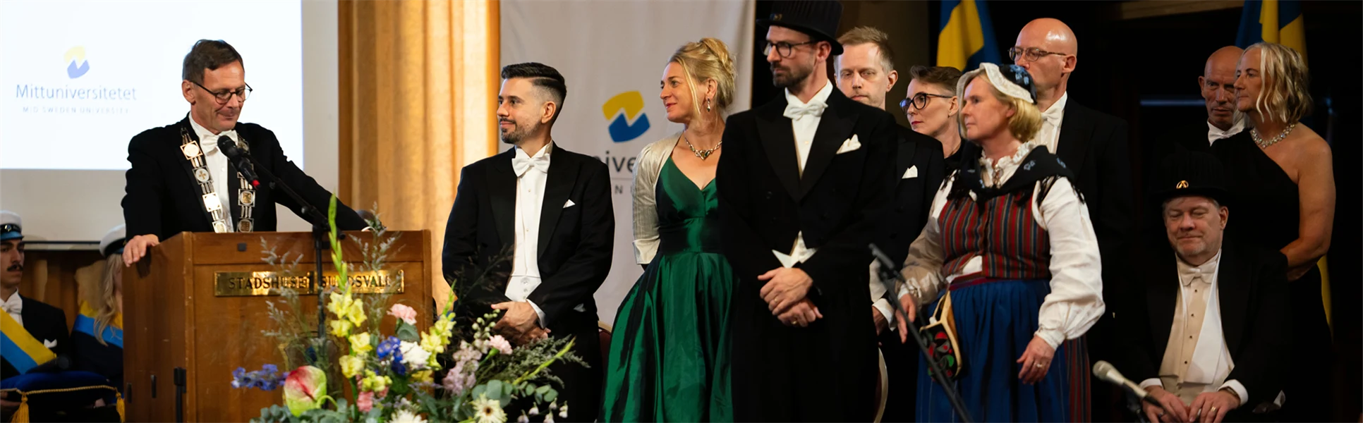 En grupp finklädda människor står på en scen.